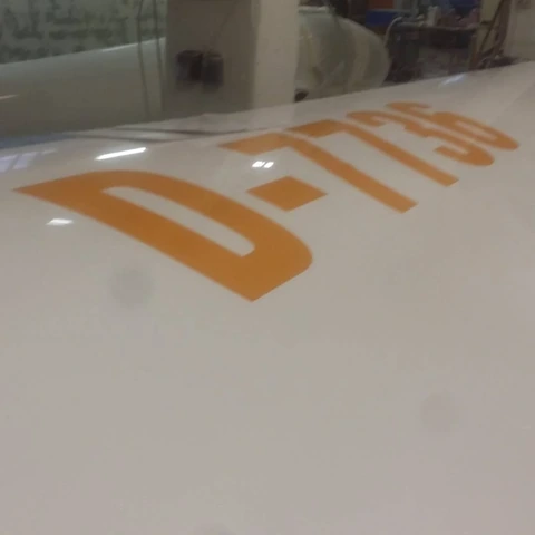 Oranžne registracijske črke na beli površini