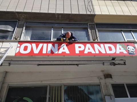 Montaža rdeče table z napisom Trgovina Panda